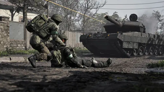 A player revives a downed team-mate in the open beside a friendly main battle tank